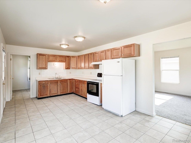 1114 Union St, Port Huron, MI 48060 - kitchen with freestanding refrigerator, range with electric stovetop, under cabinet range hood, light countertops, and brown cabinetry