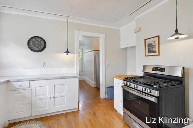 120 Union Ave SE, Grand Rapids, MI 49503 - kitchen with stainless steel gas stove, white cabinetry, light wood finished floors, decorative light fixtures, and crown molding