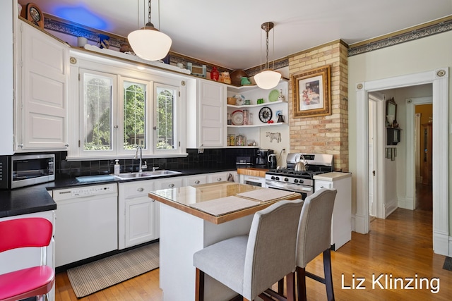 120 Union Ave SE, Grand Rapids, MI 49503 - kitchen featuring appliances with stainless steel finishes, light wood finished floors, backsplash, white cabinetry, and hanging light fixtures