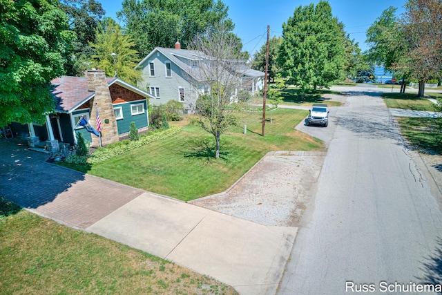 305 N Division St, Spring Lake, MI 49456 - view of front facade with driveway, a chimney, and a front lawn