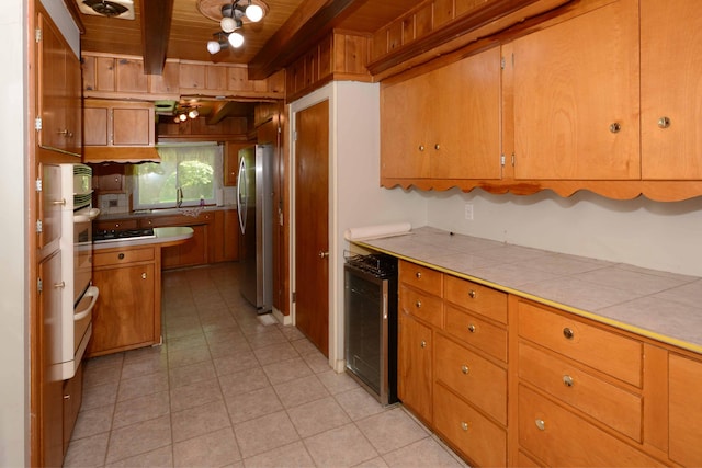 2357 River St, Kalamazoo, MI 49048 - kitchen with a wood ceiling with exposed beams, appliances with stainless steel finishes, tile countertops, brown cabinetry, and light tile patterned floors