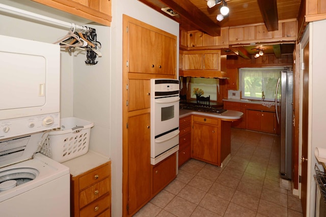 2357 River St, Kalamazoo, MI 49048 - kitchen featuring stainless steel appliances, a warming drawer, stacked washer / drying machine, light tile patterned flooring, and a peninsula