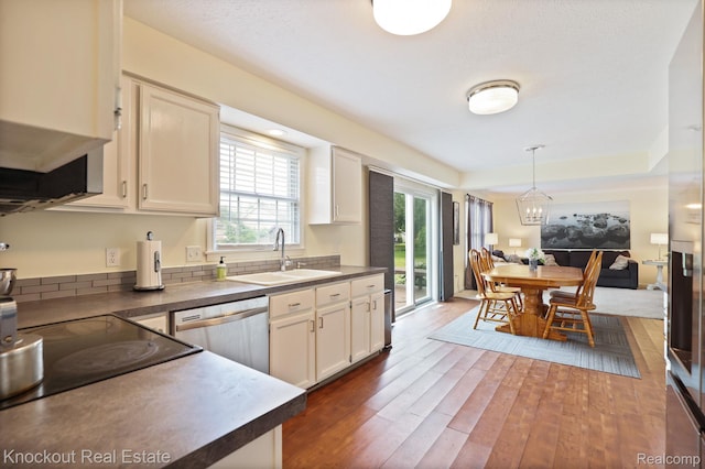 622 W Schleier St, Frankenmuth, MI 48734 - kitchen with stainless steel dishwasher, dark wood-type flooring, dark countertops, white cabinets, and hanging light fixtures