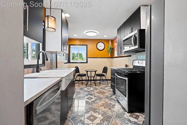 24528 Schroeder Ave, Eastpointe, MI 48021 - kitchen with stainless steel appliances, light countertops, dark cabinets, a wainscoted wall, and hanging light fixtures