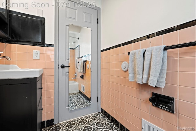 24528 Schroeder Ave, Eastpointe, MI 48021 - bathroom featuring tile walls, tile patterned flooring, vanity, a wainscoted wall, and a bathtub