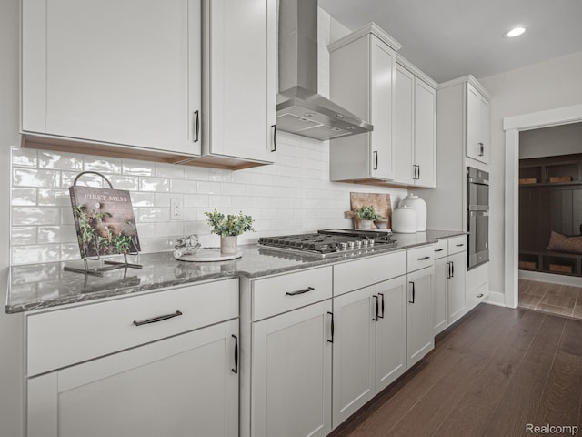 16257 Rogan Dr, Linden, MI 48451 - kitchen featuring wall chimney exhaust hood, appliances with stainless steel finishes, dark wood-style flooring, light stone counters, and decorative backsplash