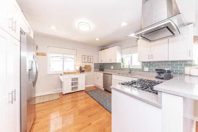 2041 Norfolk Ave, Ann Arbor, MI 48103 - kitchen featuring wall chimney exhaust hood, appliances with stainless steel finishes, white cabinets, backsplash, and light wood finished floors