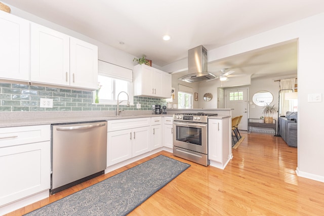 2041 Norfolk Ave, Ann Arbor, MI 48103 - kitchen featuring appliances with stainless steel finishes, island range hood, a peninsula, light countertops, and light wood finished floors