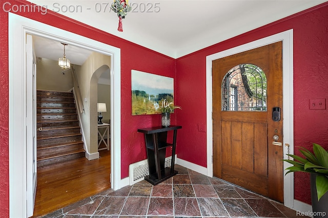 132 Illinois Ave, Pontiac, MI 48341 - foyer entrance featuring arched walkways, stairway, a textured wall, and dark stone finish floors