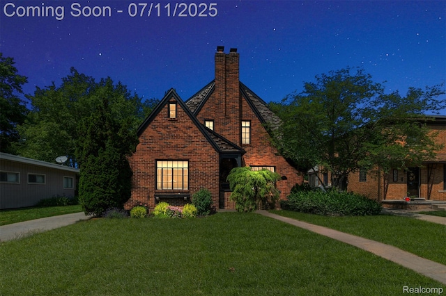 132 Illinois Ave, Pontiac, MI 48341 - tudor-style house featuring a front yard, brick siding, and a chimney