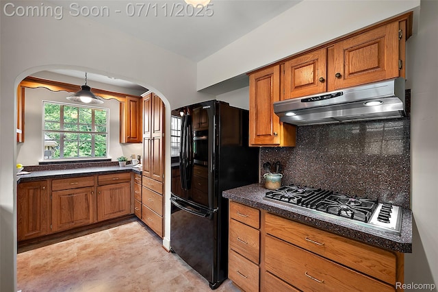 132 Illinois Ave, Pontiac, MI 48341 - kitchen featuring under cabinet range hood, arched walkways, freestanding refrigerator, stainless steel gas stovetop, and brown cabinets