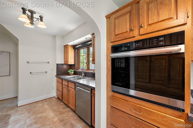 132 Illinois Ave, Pontiac, MI 48341 - kitchen with appliances with stainless steel finishes, arched walkways, brown cabinetry, dark countertops, and tasteful backsplash