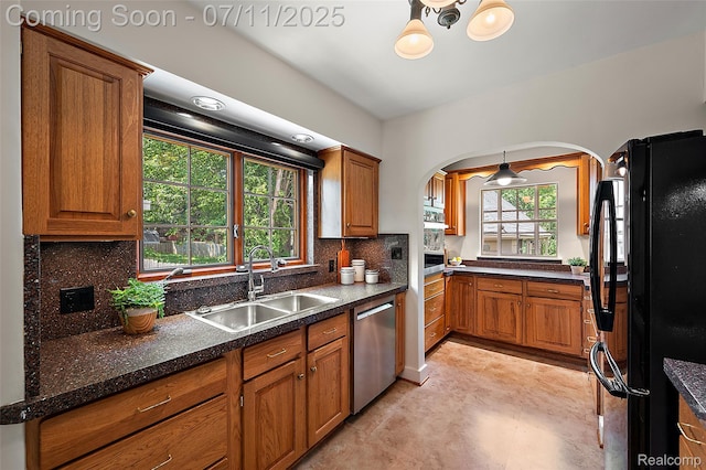 132 Illinois Ave, Pontiac, MI 48341 - kitchen featuring freestanding refrigerator, stainless steel dishwasher, brown cabinetry, and arched walkways
