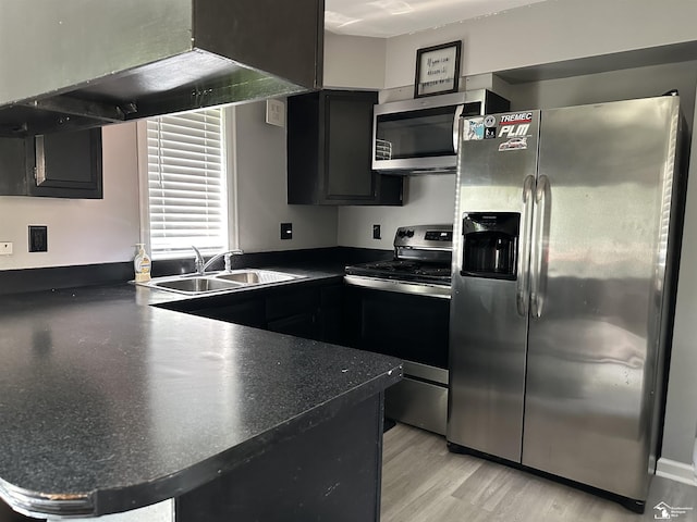 10931 Telegraph Rd, Erie, MI 48133 - kitchen with appliances with stainless steel finishes, dark countertops, dark cabinets, a peninsula, and light wood-style floors
