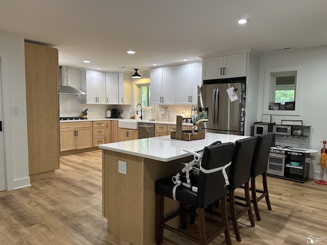 10931 Telegraph Rd, Erie, MI 48133 - kitchen featuring appliances with stainless steel finishes, wall chimney range hood, light wood-type flooring, light countertops, and a breakfast bar area