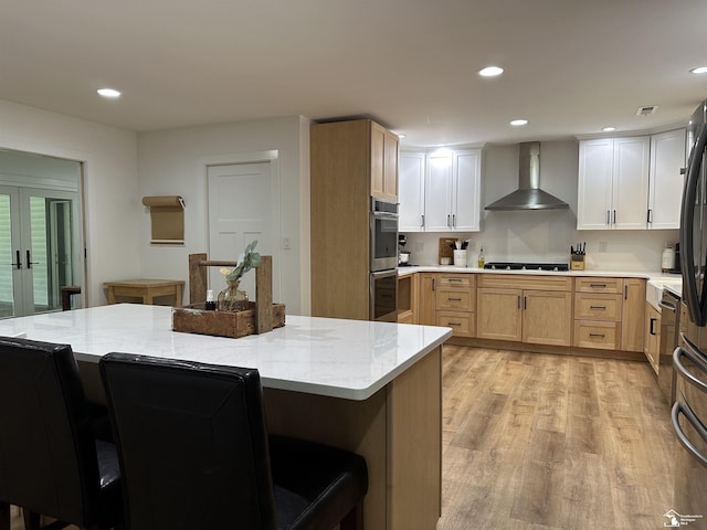 10931 Telegraph Rd, Erie, MI 48133 - kitchen with wall chimney range hood, a kitchen breakfast bar, light wood finished floors, stainless steel double oven, and light stone countertops