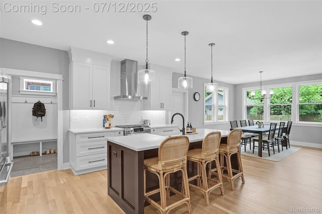 1212 Royal Ave, Royal Oak, MI 48073 - kitchen with wall chimney range hood, light wood-type flooring, light countertops, a kitchen island with sink, and recessed lighting