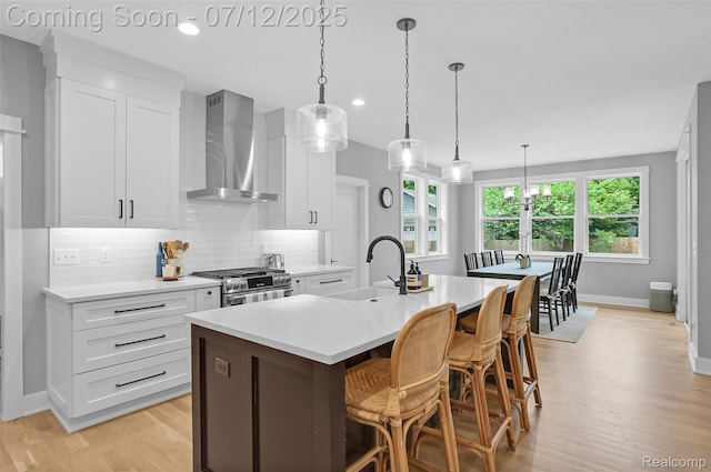 1212 Royal Ave, Royal Oak, MI 48073 - kitchen featuring wall chimney exhaust hood, high end stove, light wood-style floors, tasteful backsplash, and light countertops