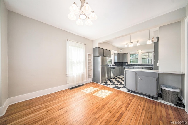 2904 Maplewood Ave, Ann Arbor, MI 48104 - kitchen with stainless steel appliances, gray cabinets, a chandelier, light wood-style floors, and a peninsula