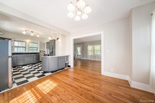 2904 Maplewood Ave, Ann Arbor, MI 48104 - kitchen with gray cabinets, freestanding refrigerator, light wood-type flooring, a chandelier, and a peninsula