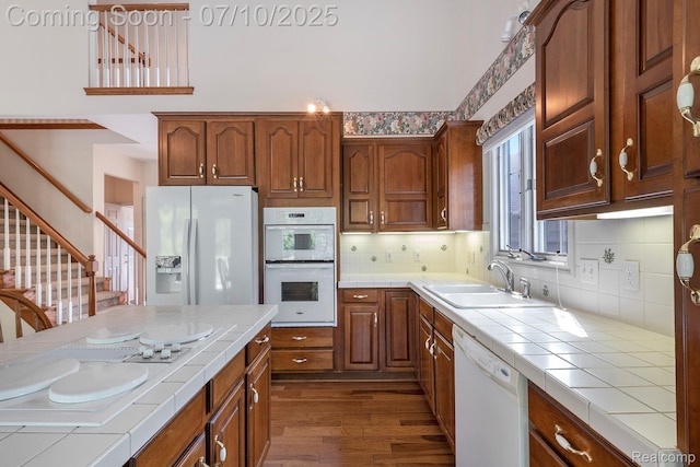 6161 Golfside Ct, Grand Blanc, MI 48439 - kitchen featuring tile countertops, white appliances, dark wood finished floors, tasteful backsplash, and brown cabinetry