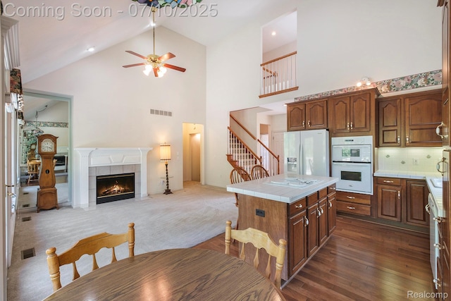 6161 Golfside Ct, Grand Blanc, MI 48439 - kitchen with tile counters, white appliances, high vaulted ceiling, a kitchen island, and a ceiling fan