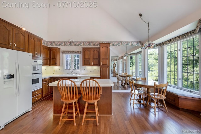 6161 Golfside Ct, Grand Blanc, MI 48439 - kitchen with white appliances, light countertops, a kitchen island, hardwood / wood-style floors, and high vaulted ceiling