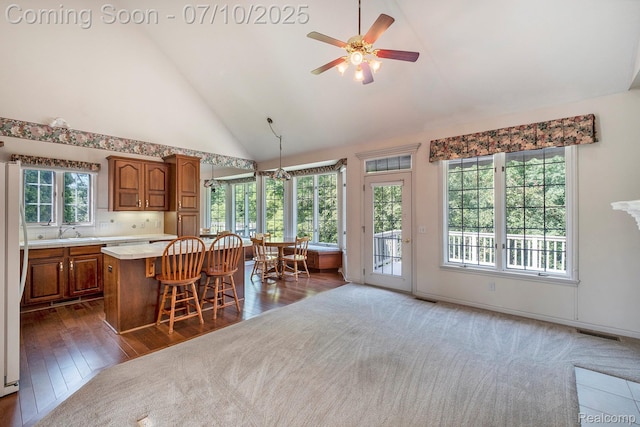 6161 Golfside Ct, Grand Blanc, MI 48439 - kitchen featuring light countertops, brown cabinets, ceiling fan, a kitchen island, and dark wood-style floors