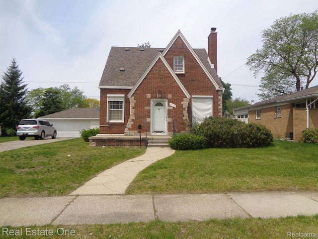 1353 N Gulley Rd, Dearborn Heights, MI 48127 - tudor-style house featuring a chimney, brick siding, a front yard, and roof with shingles