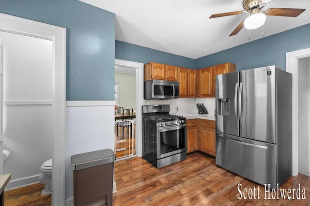 702 Griswold St SE, Grand Rapids, MI 49507 - kitchen featuring stainless steel appliances, a ceiling fan, dark wood-style flooring, tasteful backsplash, and brown cabinets