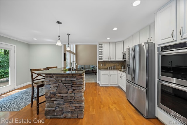31085 Chatsford St, Novi, MI 48377 - kitchen with stainless steel appliances, white cabinetry, dark countertops, light wood-type flooring, and crown molding