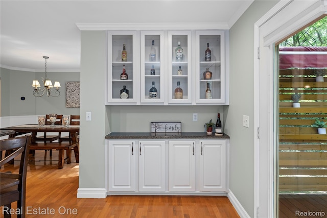31085 Chatsford St, Novi, MI 48377 - indoor dry bar featuring light wood finished floors, crown molding, hanging light fixtures, and a chandelier