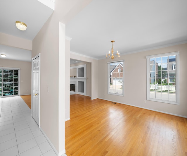 668 Boston Ct, Ann Arbor, MI 48103 - unfurnished dining area featuring a chandelier, light wood-style flooring, a glass covered fireplace, and crown molding