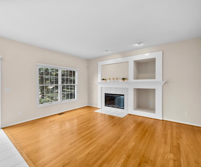 668 Boston Ct, Ann Arbor, MI 48103 - unfurnished living room with wood finished floors and a tiled fireplace