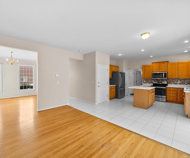 668 Boston Ct, Ann Arbor, MI 48103 - kitchen featuring appliances with stainless steel finishes, open floor plan, a chandelier, light wood finished floors, and light countertops