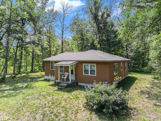 565 E Rockford Rd, Idlewild, MI 49642 - bungalow-style home with a front lawn, a chimney, and a shingled roof