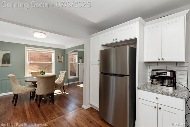 2182 Hawthorne Rd, Detroit, MI 48236 - kitchen featuring freestanding refrigerator, arched walkways, light stone countertops, dark wood-type flooring, and white cabinets