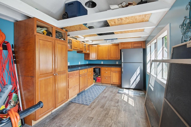 5090 Schrah Dr, Munith, MI 49259 - kitchen featuring freestanding refrigerator, light wood-type flooring, dark countertops, brown cabinets, and beamed ceiling