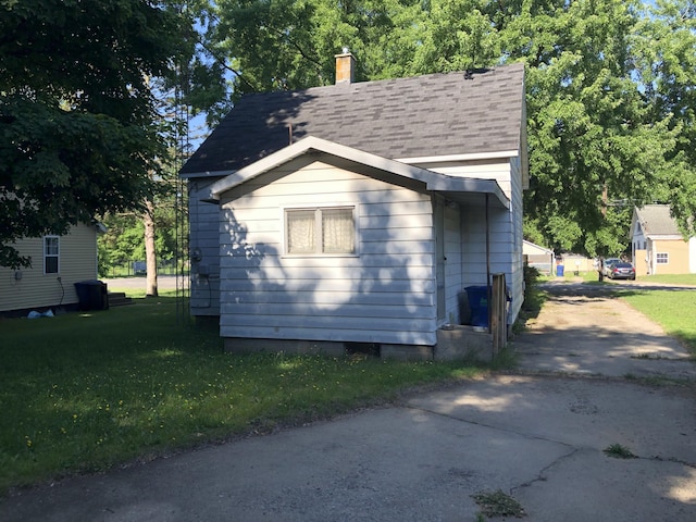 1483 Rose Ave, Benton Harbor, MI 49022 - view of home's exterior with a chimney, a shingled roof, a lawn, and driveway