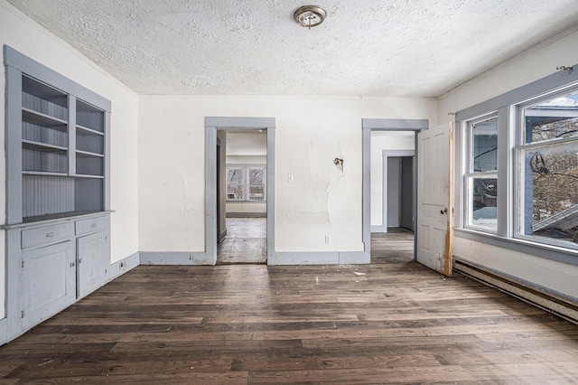 174 Cherry St, Battle Creek, MI 49017 - empty room with a textured ceiling, wood finished floors, plenty of natural light, built in shelves, and a baseboard heating unit