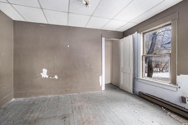 174 Cherry St, Battle Creek, MI 49017 - empty room with wood-type flooring, a baseboard radiator, and a paneled ceiling