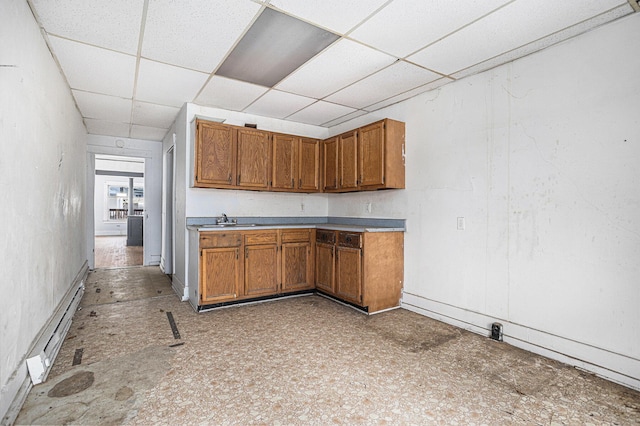 174 Cherry St, Battle Creek, MI 49017 - kitchen with baseboard heating, a paneled ceiling, brown cabinets, and light countertops