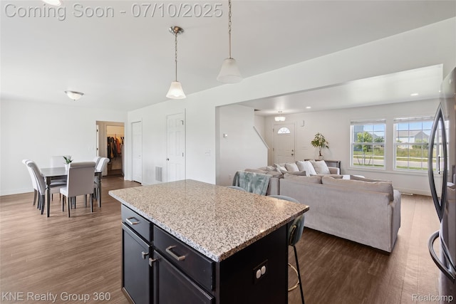 7057 Primrose Ln, Grand Blanc, MI 48439 - kitchen with a kitchen island, dark wood-style flooring, open floor plan, pendant lighting, and freestanding refrigerator