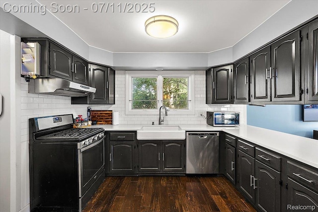 4674 Chapel Dr, Troy, MI 48085 - kitchen featuring appliances with stainless steel finishes, under cabinet range hood, dark wood-type flooring, light countertops, and decorative backsplash