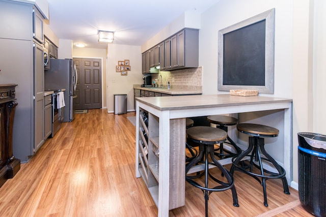 37516 N Laurel Park Dr, Livonia, MI 48152 - kitchen featuring stainless steel range with electric cooktop, light wood finished floors, light countertops, decorative backsplash, and a breakfast bar