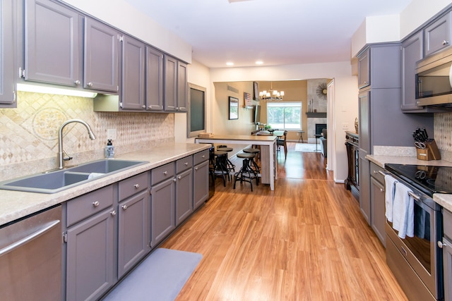 37516 N Laurel Park Dr, Livonia, MI 48152 - kitchen with stainless steel appliances, light wood-style floors, light countertops, a chandelier, and tasteful backsplash