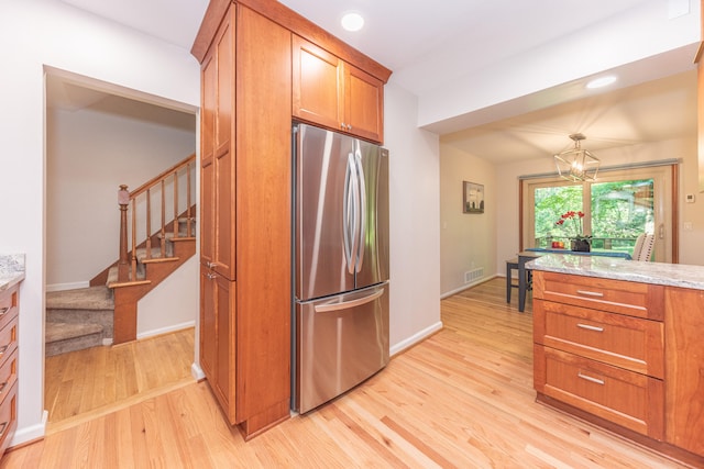 2728 Kimberley Rd, Ann Arbor, MI 48104 - kitchen featuring freestanding refrigerator, brown cabinets, light wood finished floors, a chandelier, and recessed lighting