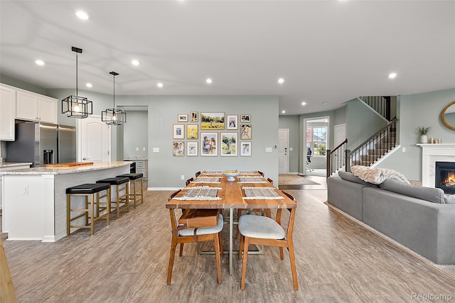 3860 Summit Dr, Sterling Heights, MI 48314 - dining area with recessed lighting, light wood-style floors, a warm lit fireplace, and stairs