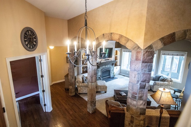 7380 Vassar Rd, Grand Blanc, MI 48439 - bedroom with a chandelier, wood finished floors, a towering ceiling, a stone fireplace, and arched walkways