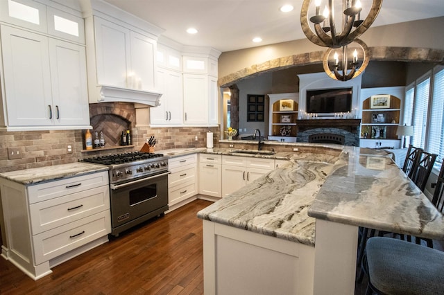 7380 Vassar Rd, Grand Blanc, MI 48439 - kitchen with luxury range, a fireplace, a chandelier, recessed lighting, and dark wood-type flooring